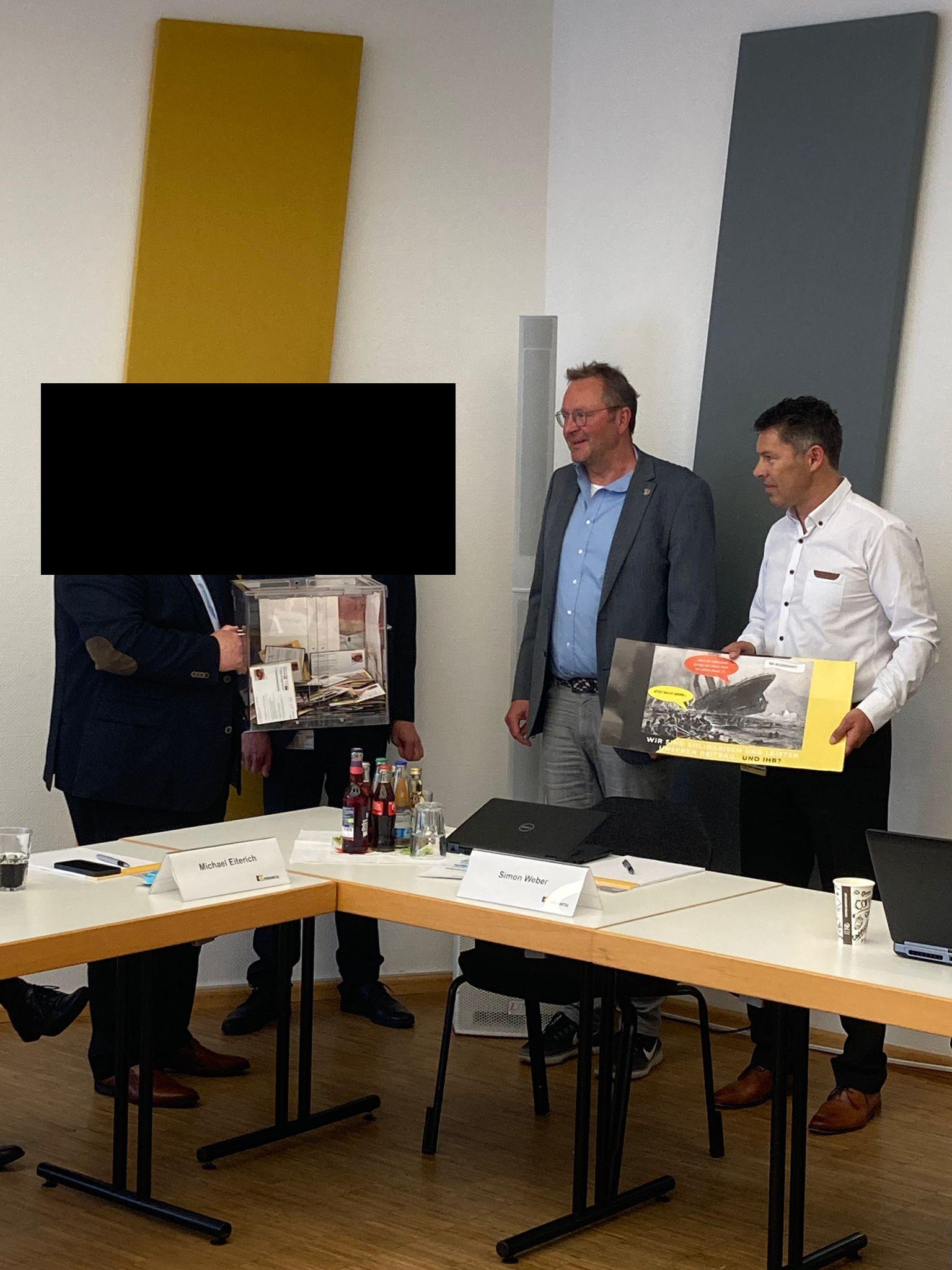 schwarzer Balken über Hr. Pasler und Hr. Weber bei der Postkartenübergabe Kennametal