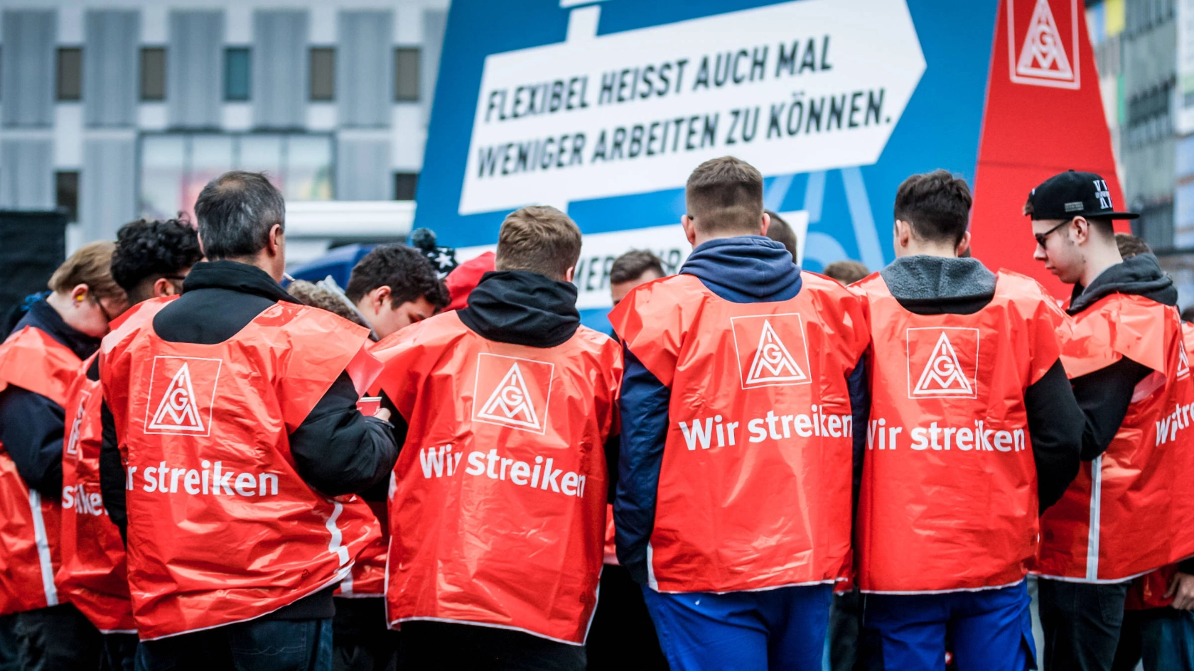 Eine Gruppe junge Männer mit roten Streikwesten.