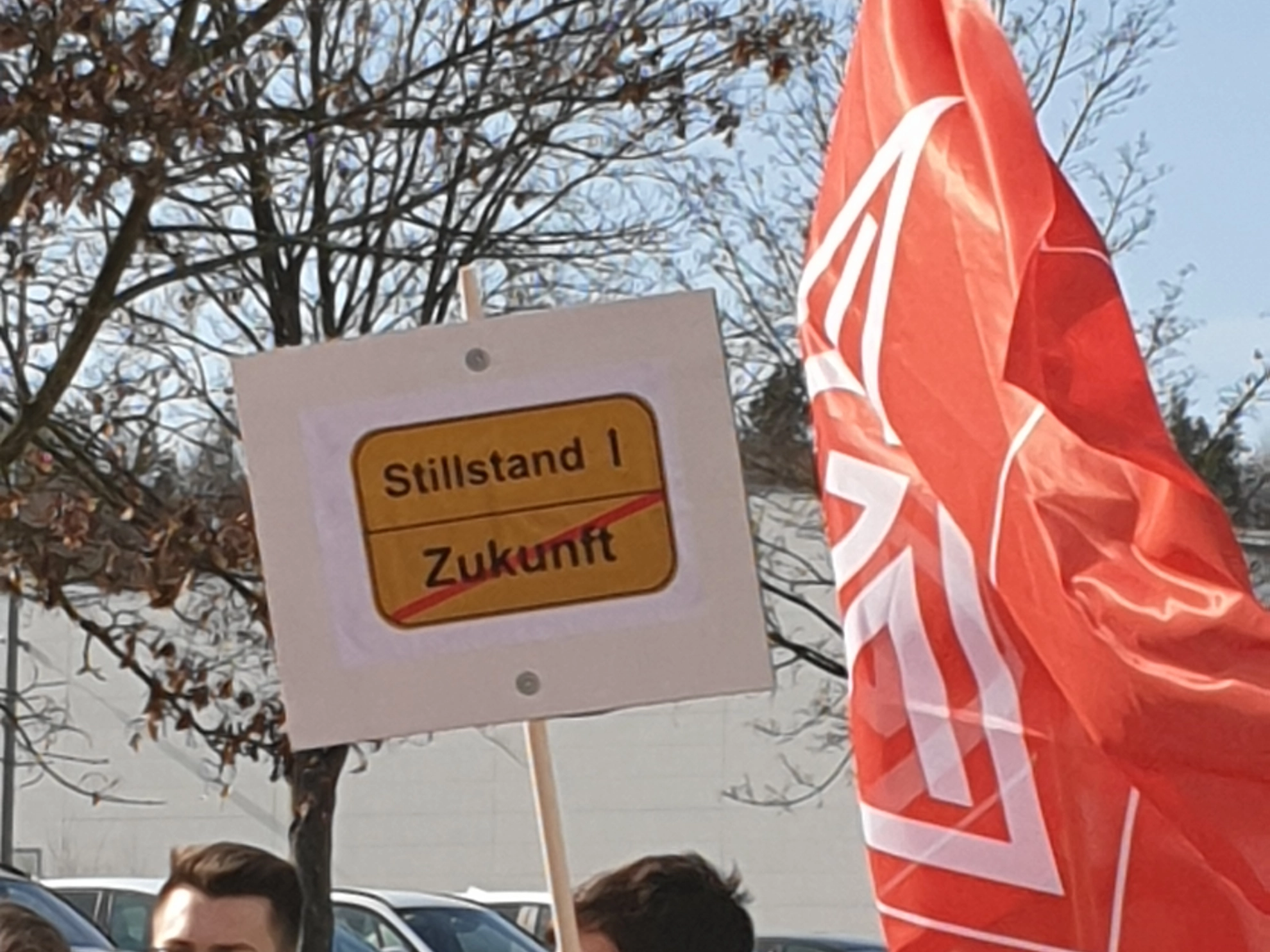 Metaller*innen halten Schild Stillstand/Zukunft