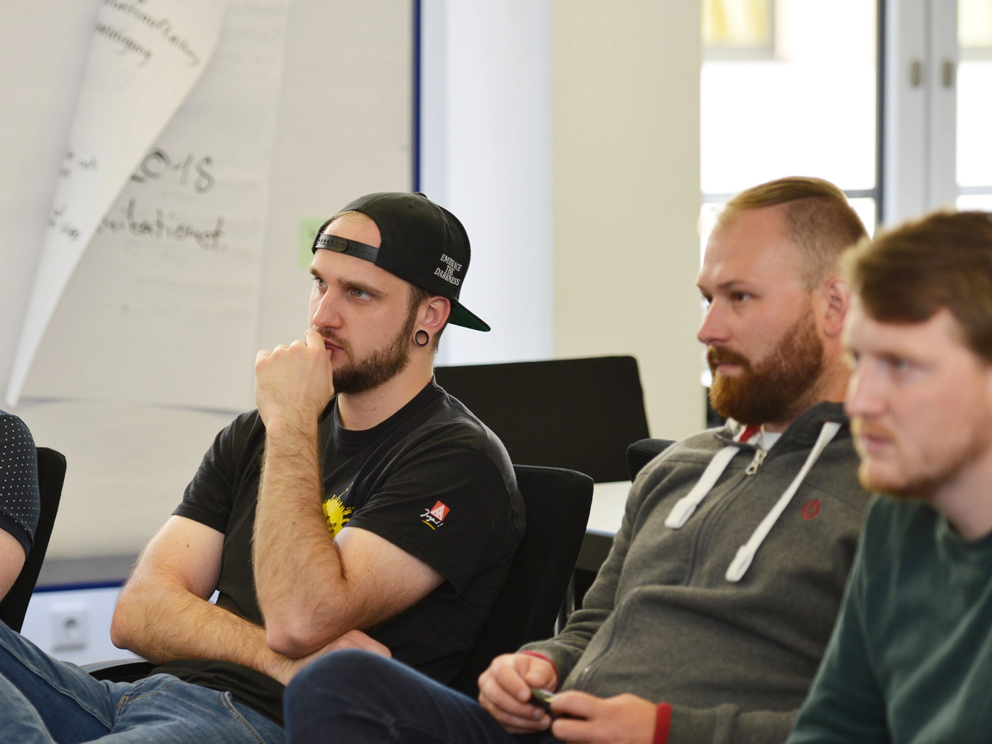 Junge Aktive sitzen während eines Seminars im Stuhlkreis und hören zu.