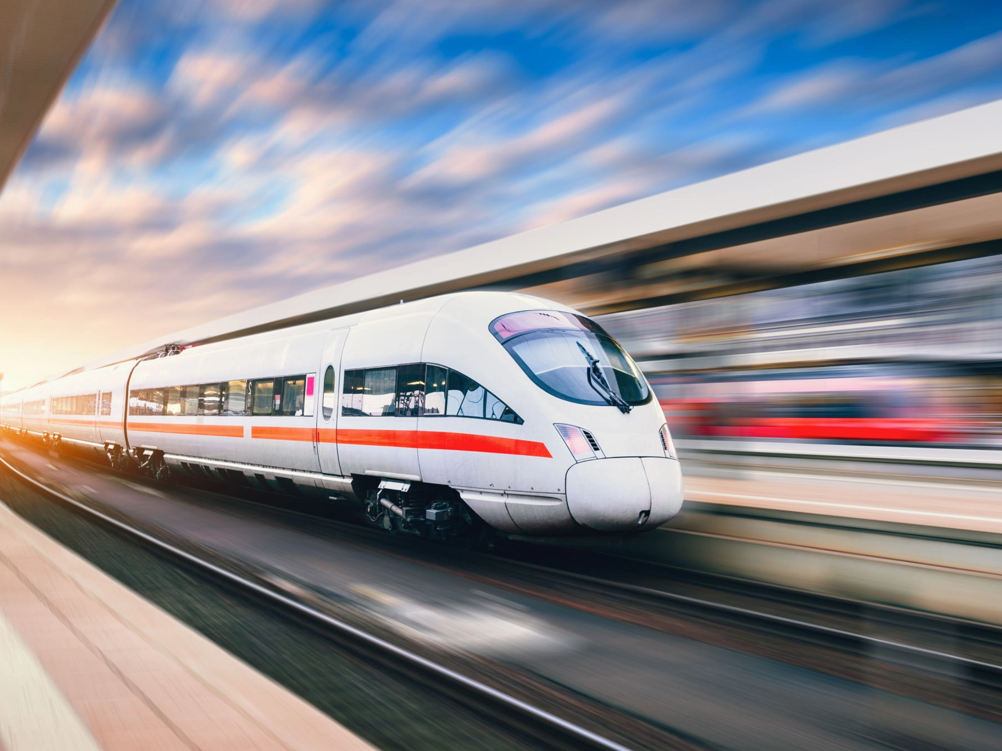 ICE Zug passiert einen Bahnhof bei Sonnenuntergang