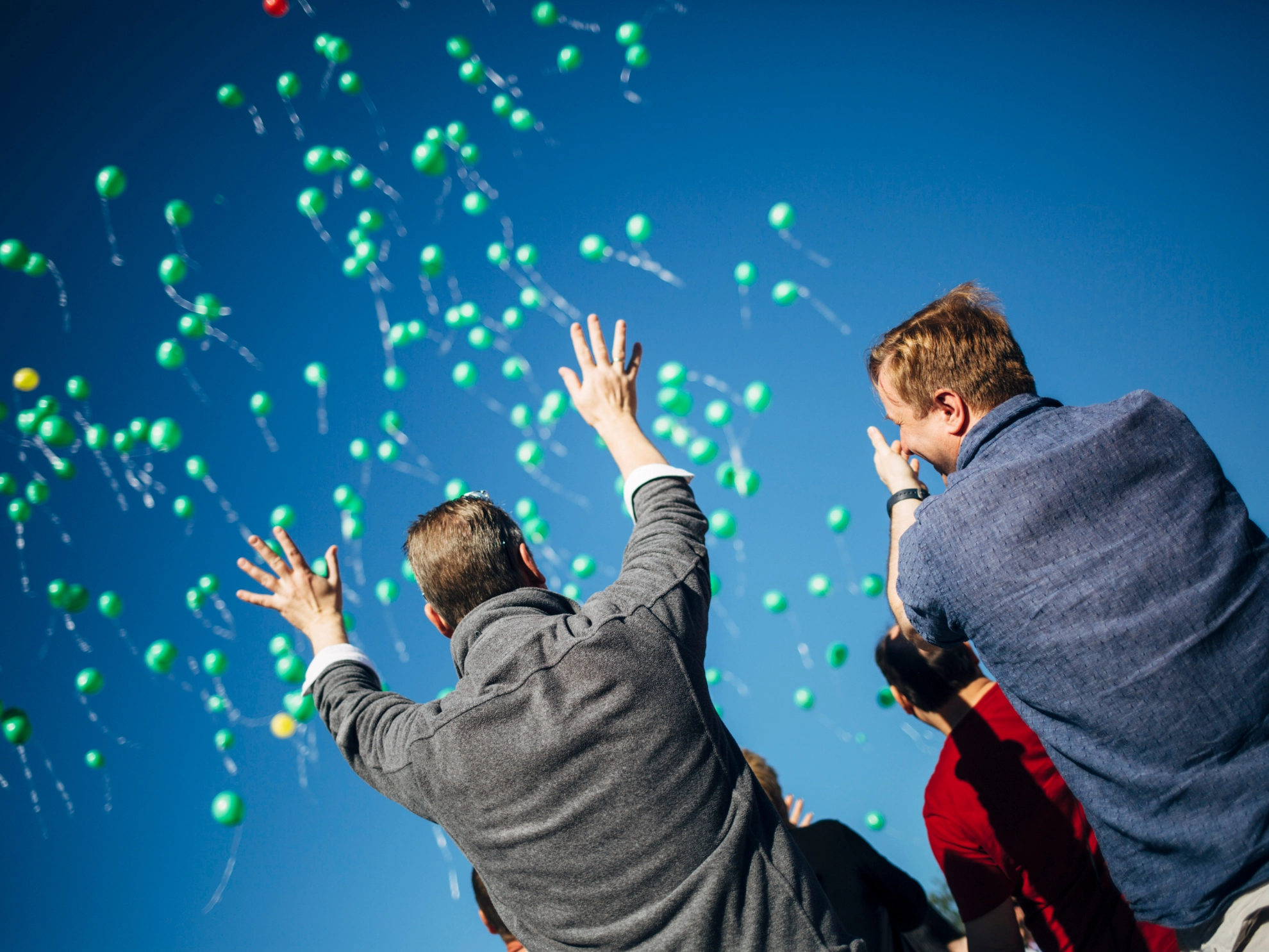Zwei Menschen mit grünen Luftballons_Symbolbild