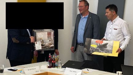 schwarzer Balken über Hr. Pasler und Hr. Weber bei der Postkartenübergabe Kennametal